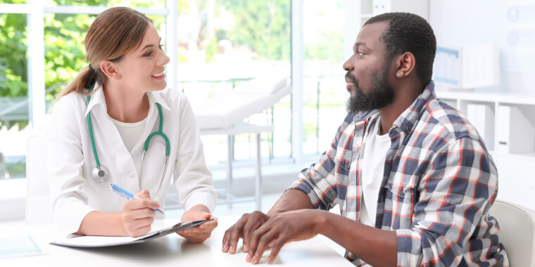 Young doctor speaking to African-American patient in hospital