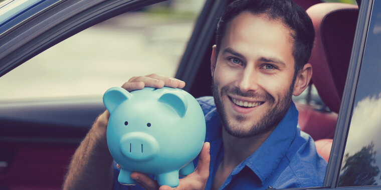 Man holding a piggy bank inside car