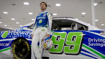 Daniel Suarez with his helmet standing beside his car with Freeway Insurance branding