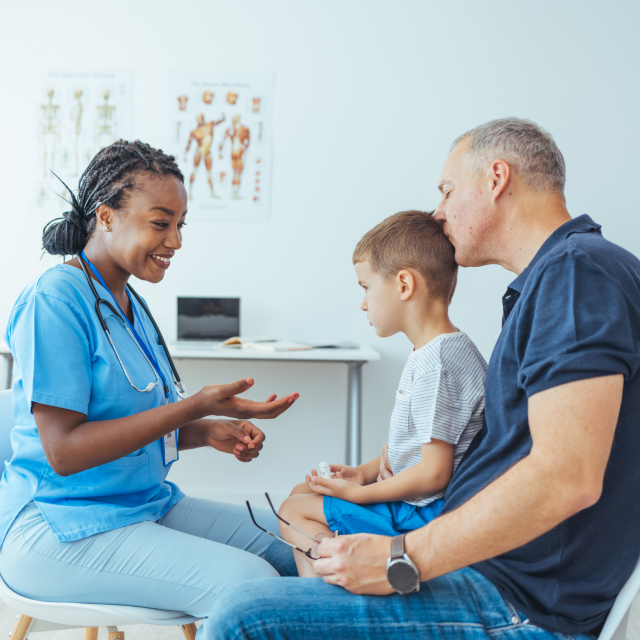 Doctor attending a child seated on his father's lap