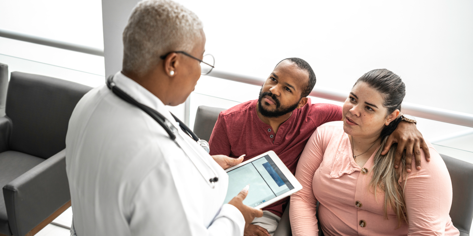 African American doctor talking to a couple about health care in waiting room