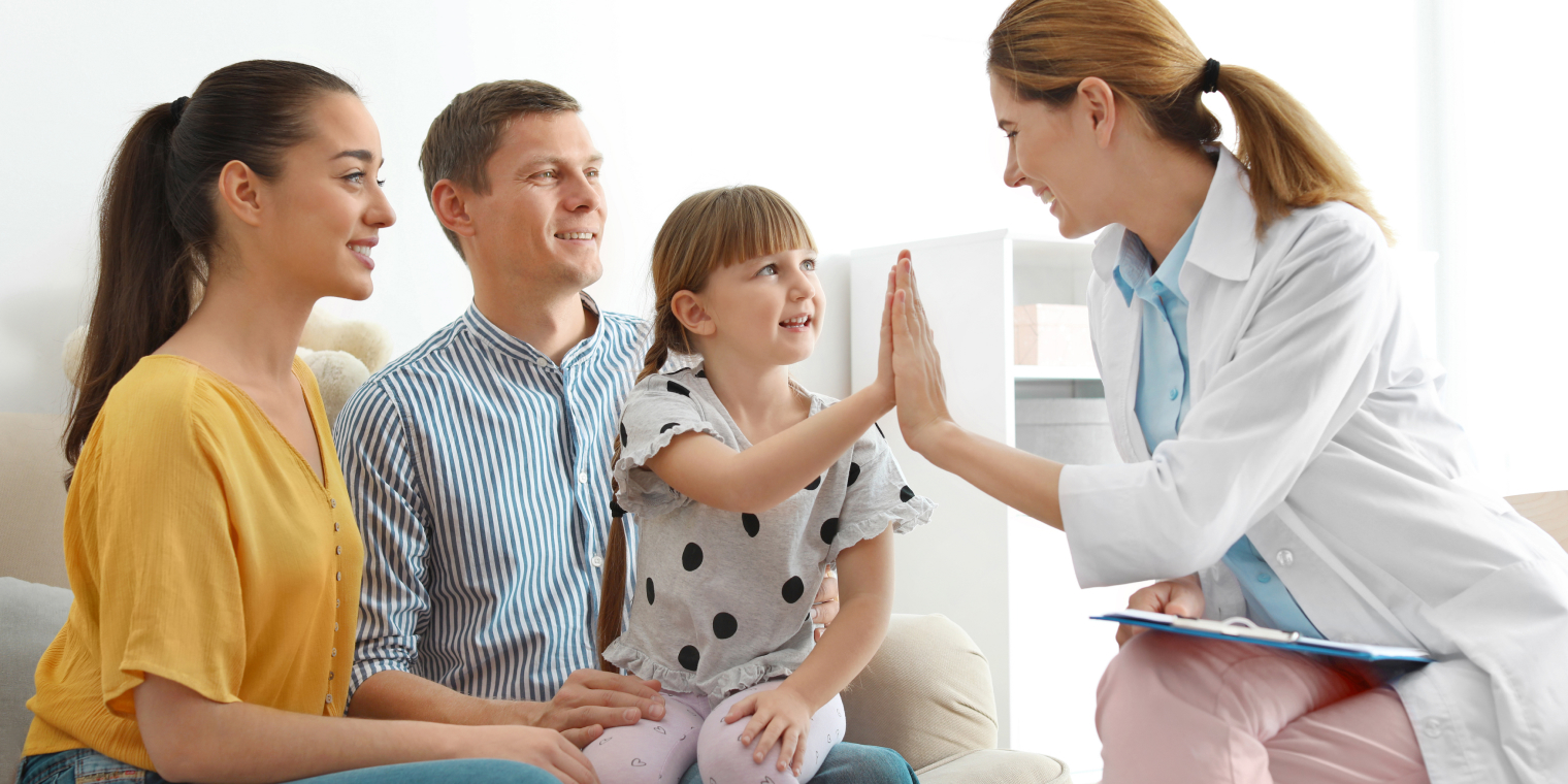 Doctor doing a high five with girl and her family in the doctors office