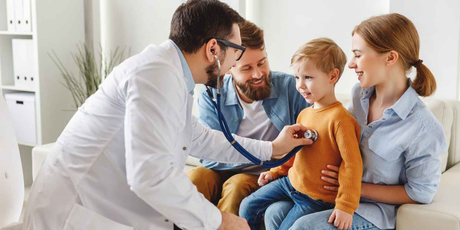 Doctor checking the heartbeat of boy with his family in the doctors office