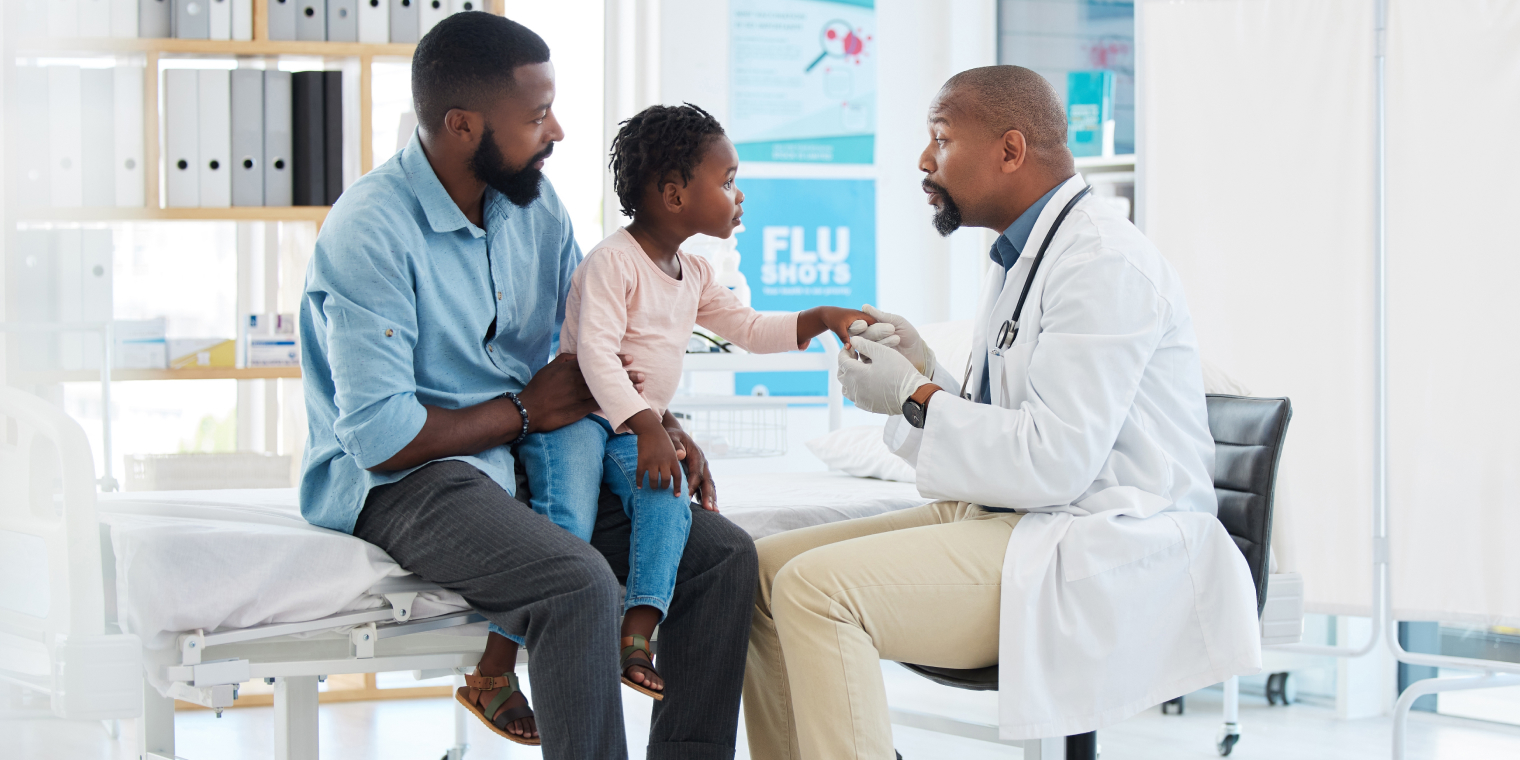 Doctor tending an African American child with his parent in the doctors office
