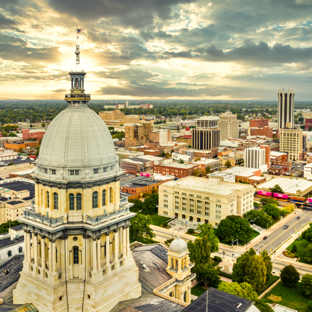 Aerial view of the Illinois State Capitol and the Springfield skyline at sunset.