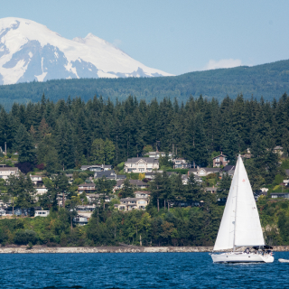Mount Baker with a sailboat and houses in the Bellingham area