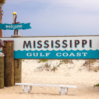 Welcome to the Mississippi Gulf Coast sign on a sandy beach in Gulfport