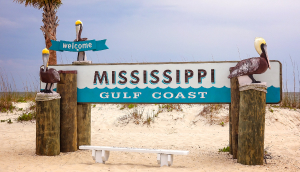 Welcome to the Mississippi Gulf Coast sign on a sandy beach in Gulfport