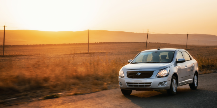 Chevrolet Cobalt plateado avanzando en la carretera durante el atardecer. 
