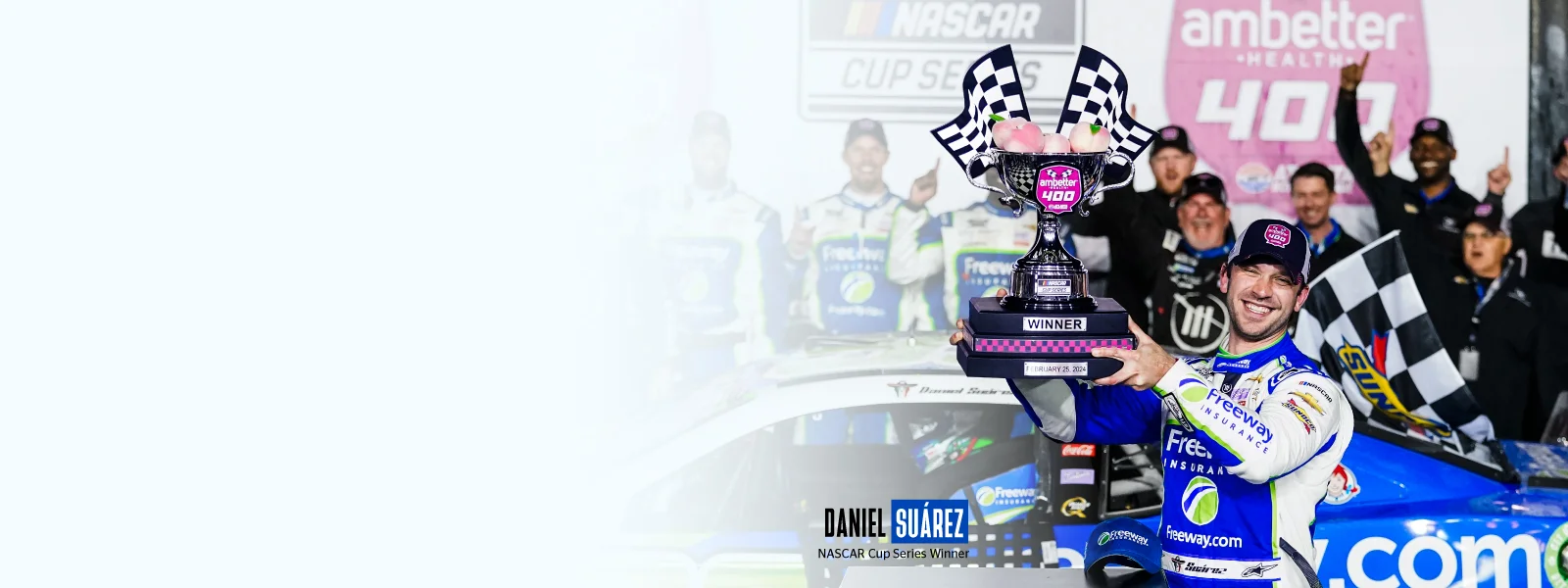 Daniel Suárez proudly wearing the Freeway Insurance uniform and raising the checkered flag after winning his second Nascar Cup Series.