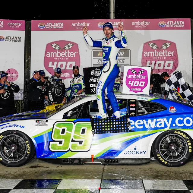 Daniel Suárez standing on the #99 Freeway Insurance Chevy Camaro to celebrate his victory at the Atlanta Motor Speedway.