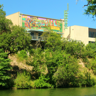 Kerrville, TX and Happy city sign over a river with trees and nature surrounding: Lose Your Heart to the Hills with cheap car insurance in Texas.