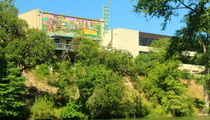 Kerrville, TX and Happy city sign over a river with trees and nature surrounding: Lose Your Heart to the Hills with cheap car insurance in Texas.