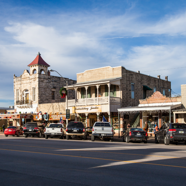 The Magic Mile Main Street with retail stores, people walking, dining, and parked cars: Fritztown cheap car insurance in Texas.