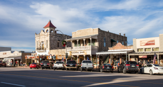 The Magic Mile Main Street with retail stores, people walking, dining, and parked cars: Fritztown cheap car insurance in Texas.