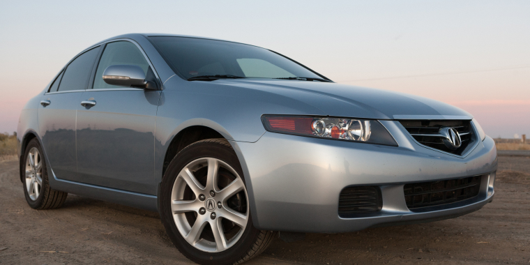 Closeup of silver Acura TSX on dirt road in a countryside in the evening.