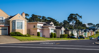 A row of colorful houses lines the street in suburban Daly City, California: Cheap car insurance in The Golden State.