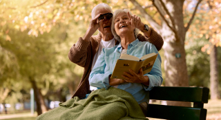 Park, bench, and binoculars with a senior couple birdwatching together outdoors in nature during summer. Spring, love, and book with a mature man and woman bonding while sitting in a garden for the view: Cheap car insurance in Mission, Texas.