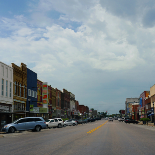 Old buildlings and cars parked on the curb side at the main street of Denison, Texas: Cheap car insurance in Denison, Texas.