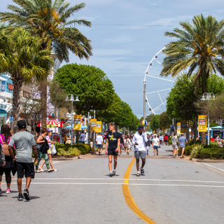 A view of the town of Panama City from middle of a street. Concrete road with center stripe and pedestrians, USA – cheap car insurance in Panama City, Florida