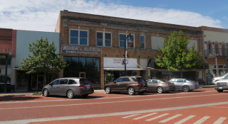 A brick-paved street with old buildings and cars parked in the roadside in Sulphur Springs, Texas: cheap car insurance in Texas.