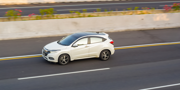 White Honda HR- crossover driving fast on trans jawa highway toll road blurry in motion. 