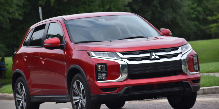 A portrait of a red Mitsubishi Outlander luxury SUV cruising at a nature reserve in Houston, Texas.