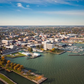Boats sit idle docked to piers in a harbor along the coast just outside of downtown Sandusky, Ohio on a sunny autumn day.
