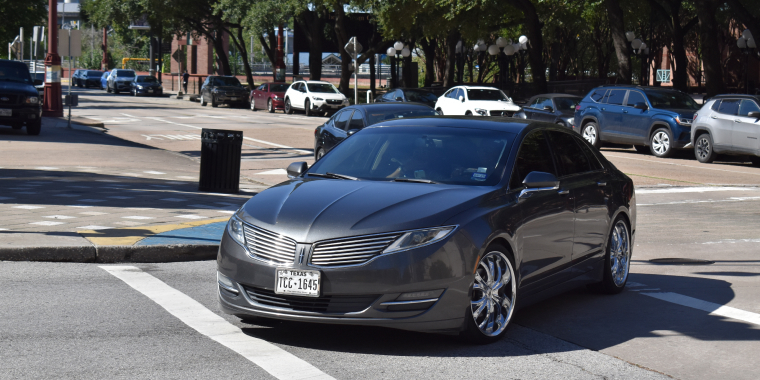 A Lincoln MKS equipped with custom wheels, cruising in the downtown financial district of Houston, Texas, USA – cheap car insurance