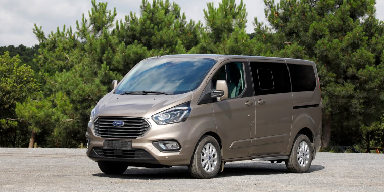 Golden Ford Transit Connect parked in the middle of a street in front of trees in Istambul – Ford, cheap car insurance.