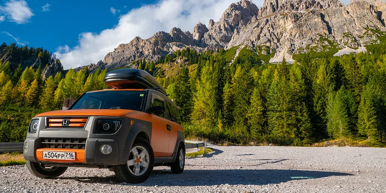 Bright orange Honda Element in the Alps mountains – cheap car insurance. 