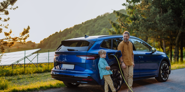 Father and his son charging electric car during their trip.