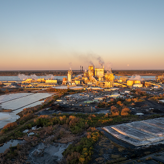 Early morning light bathes a paper mill in Brunswick, with storage and industrial activity – cheap car insurance in Georgia.