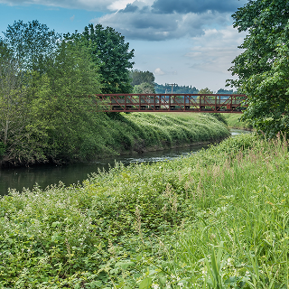 A rusted metal bridge spans the Green River in Kent – cheap car insurance in Washington.
