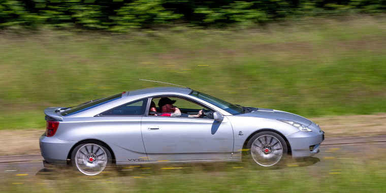 Silver Toyota Celica car driving on a British country road, cheap car insurance.