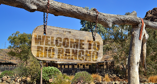 old vintage wood signboard with text welcome to rio rancho hanging on a branch