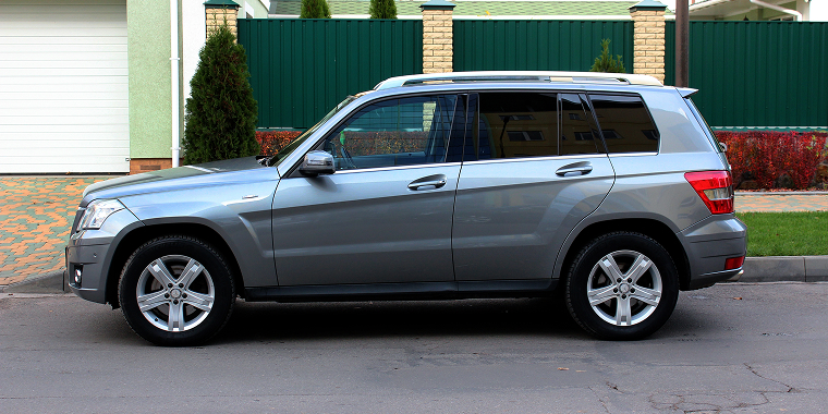 Grey Mercedes-Benz GLK-Class SUV parked on a city street with green trees in the background – cheap car insurance