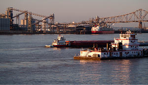 Port Allen, Louisiana Mississippi River industrial waterfront with tugboats, barge traffic, and bridge at sunset