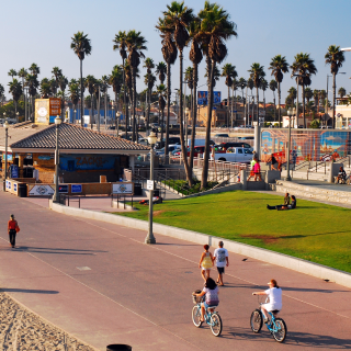 People enjoy a sunny summer day biking and walking on the bike path near the coast in Huntington Beach, California.