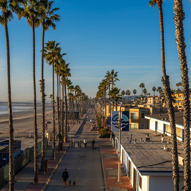 Aerial view of Oceanside, California, featuring a palm tree-lined street along the beach