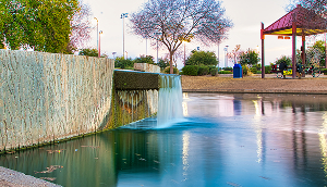 Water flowing through Rio Vista Park in Peoria, Arizona, surrounded by rocks and greenery – cheap car insurance in Arizona.