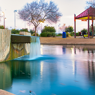 Water flowing through Rio Vista Park in Peoria, Arizona, surrounded by rocks and greenery – cheap car insurance in Arizona.