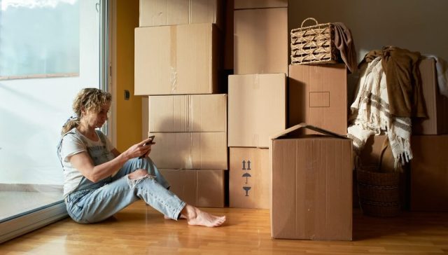 Renter surrounded by moving boxes while reviewing a renters insurance guide