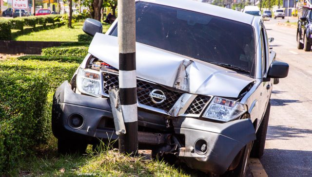 Car crashed into a city utility pole, causing damaged city property and visible front-end vehicle damage.