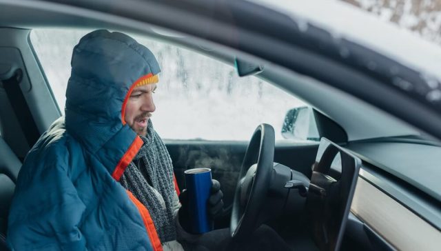 Man bundled in winter clothing inside a freezing car, trying to start your car in extreme cold.