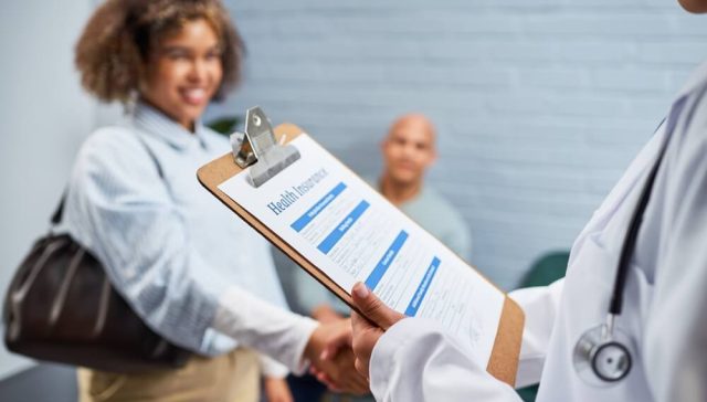 Doctor reviewing a health insurance form while meeting with patients during Covered California open enrollment.