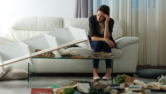 Woman looking at damaged belongings in her apartment while considering if renters insurance is a money saver or unnecessary expense.