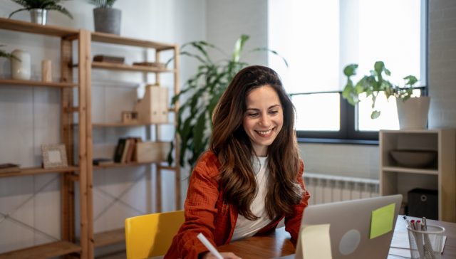 Woman working at a laptop in a home office, illustrating insurance for your home business.