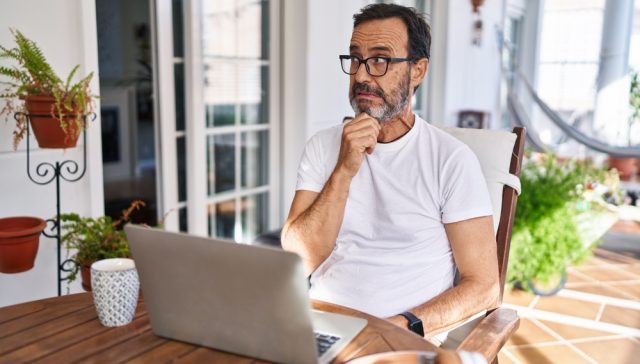 Man reviewing a laptop at home looking concerned, illustrating common home insurance mistakes when choosing or updating coverage.