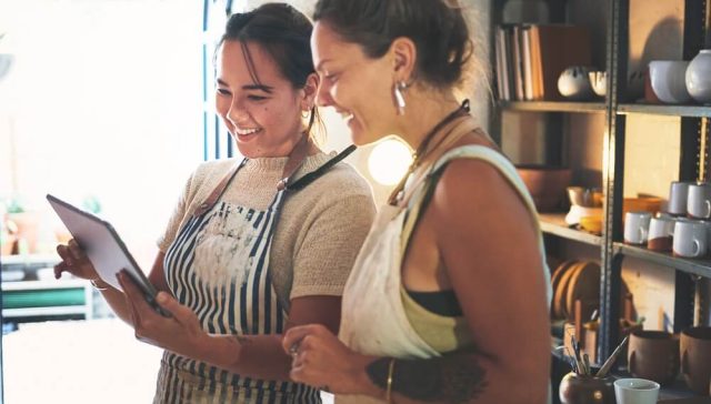 Small business owners reviewing orders on a tablet, representing online business insurance for handmade and creative businesses.